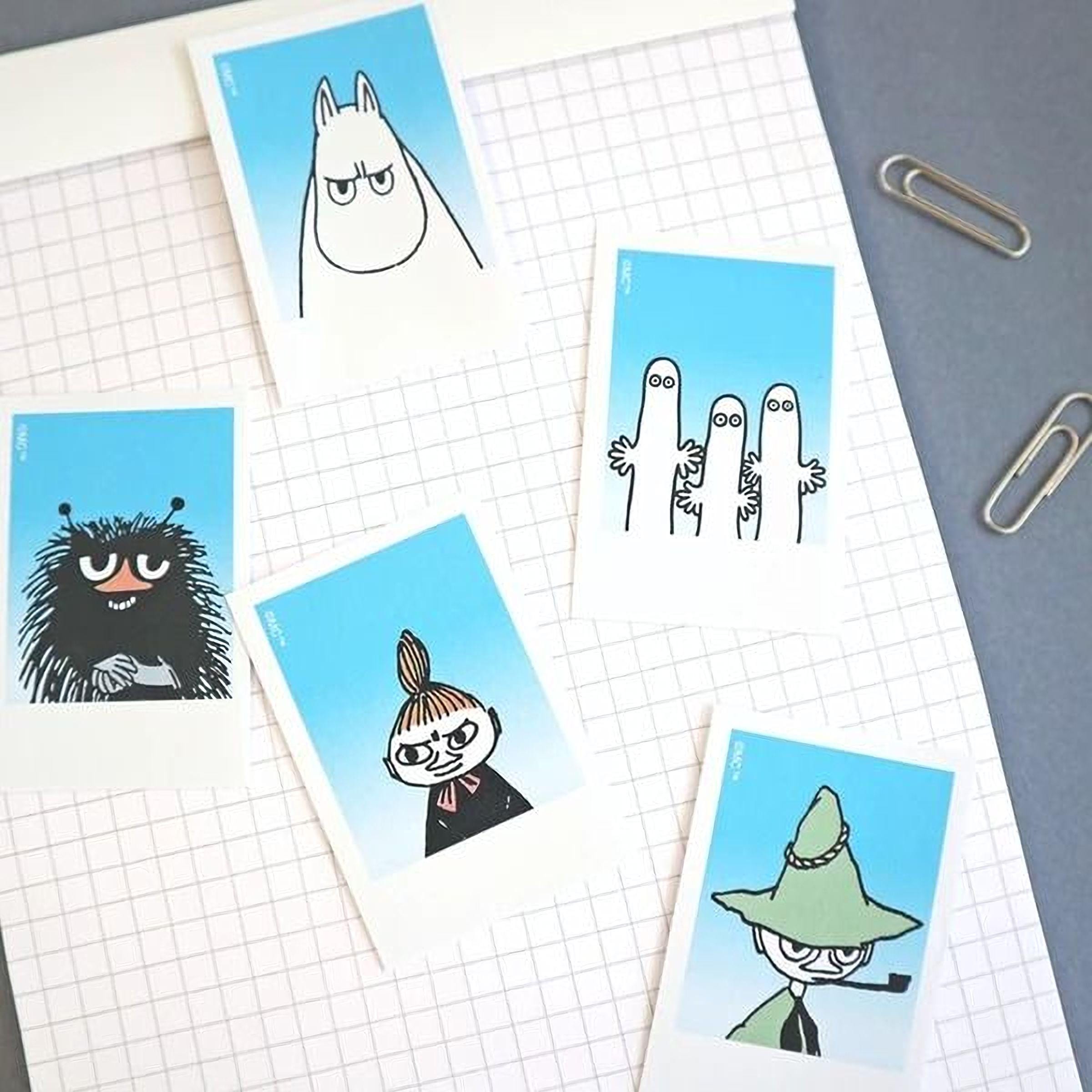 a collection of cartoon character illustrations on a grid-like background, with a pair of silver clips visible in the top right corner.