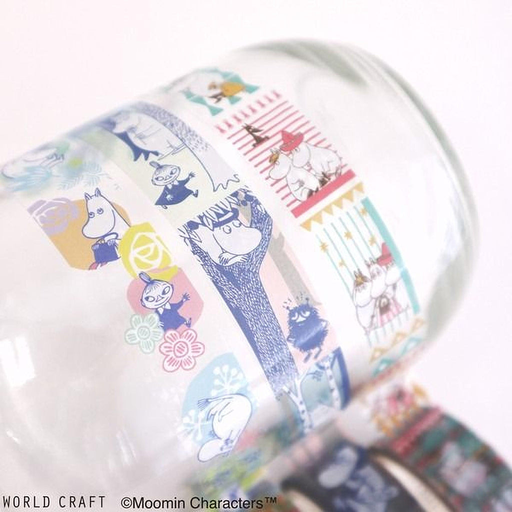 A close-up view of a colorful, patterned glass mug with various cartoon character designs and illustrations printed on it.