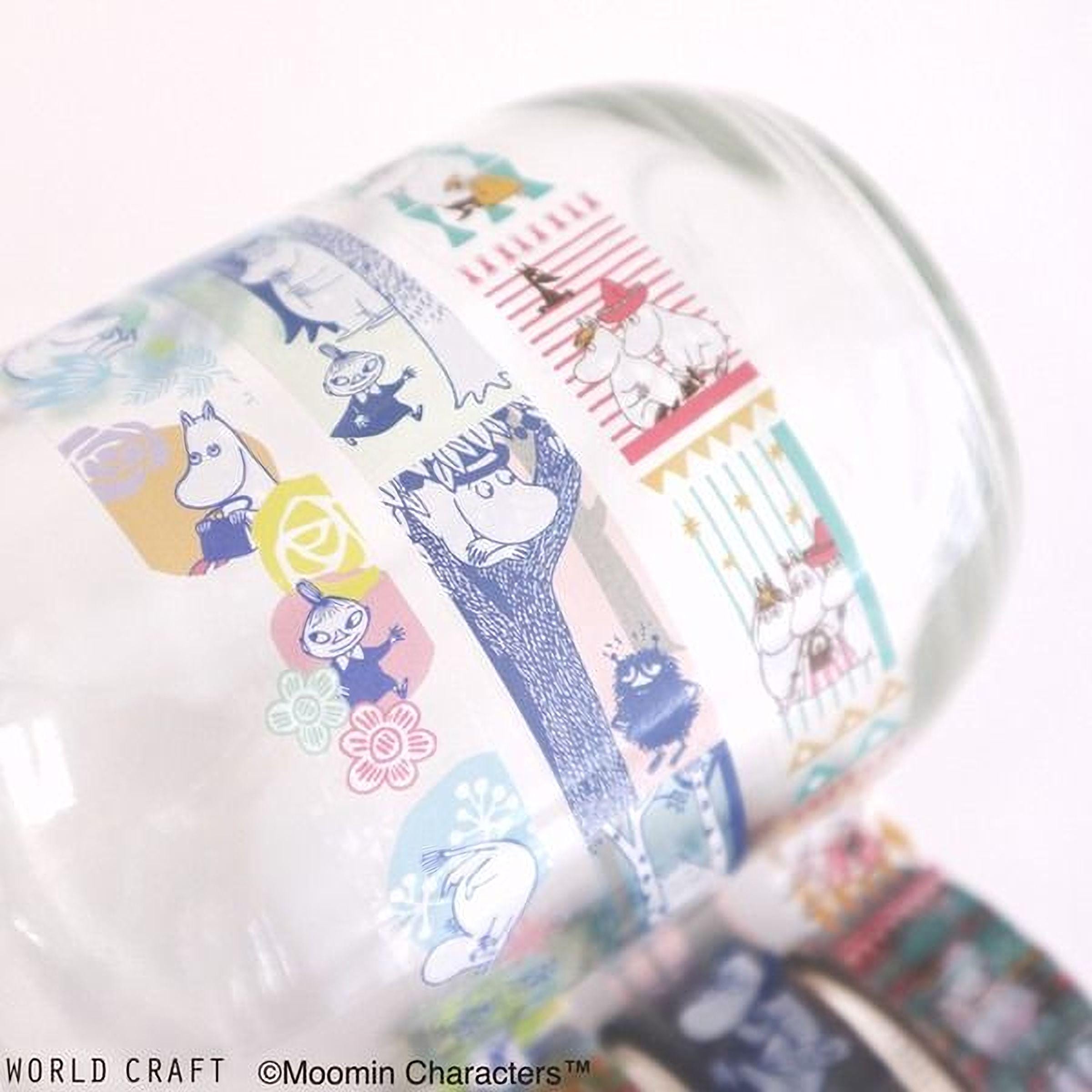 A close-up view of a colorful, patterned glass mug with various cartoon character designs and illustrations printed on it.