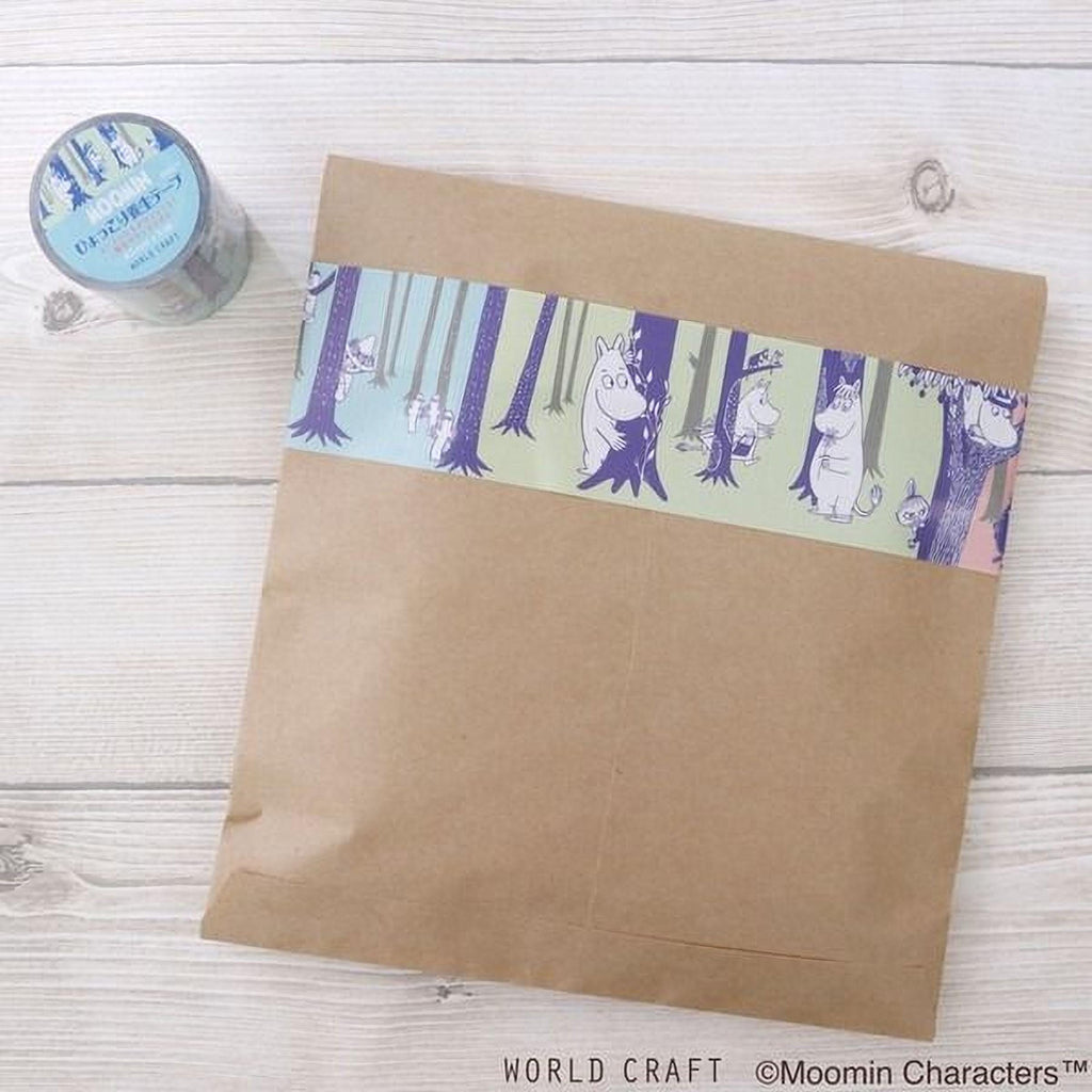 A brown envelope with a colorful, cartoonish forest-themed decal on it, placed on a wooden surface next to a roll of tape.