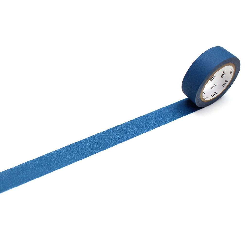 A roll of blue tape with a white label is lying on a white surface, with the tape partially unrolling and extending across the image.