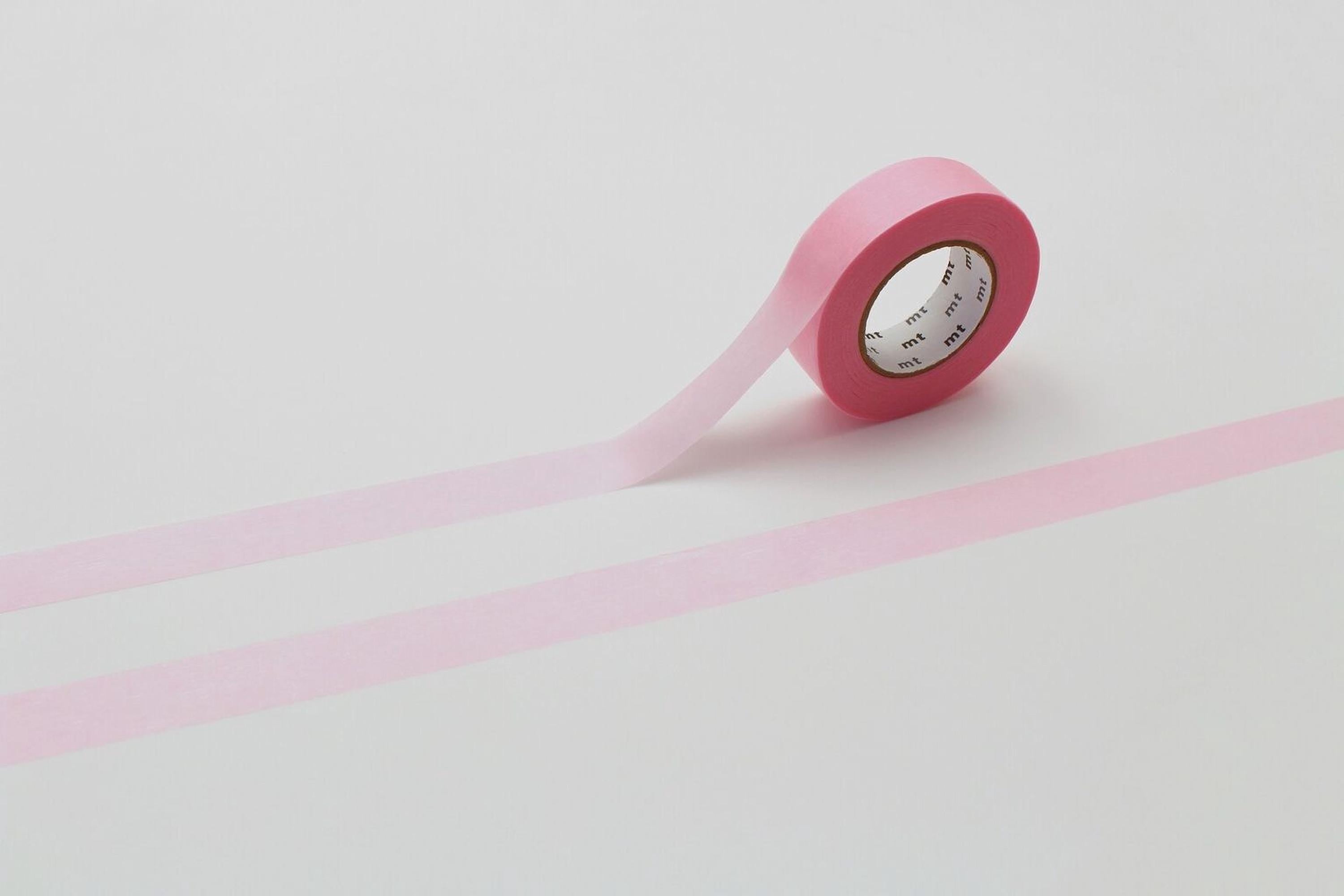 A pink roll of tape is lying on a white surface, with a pink line running across it.