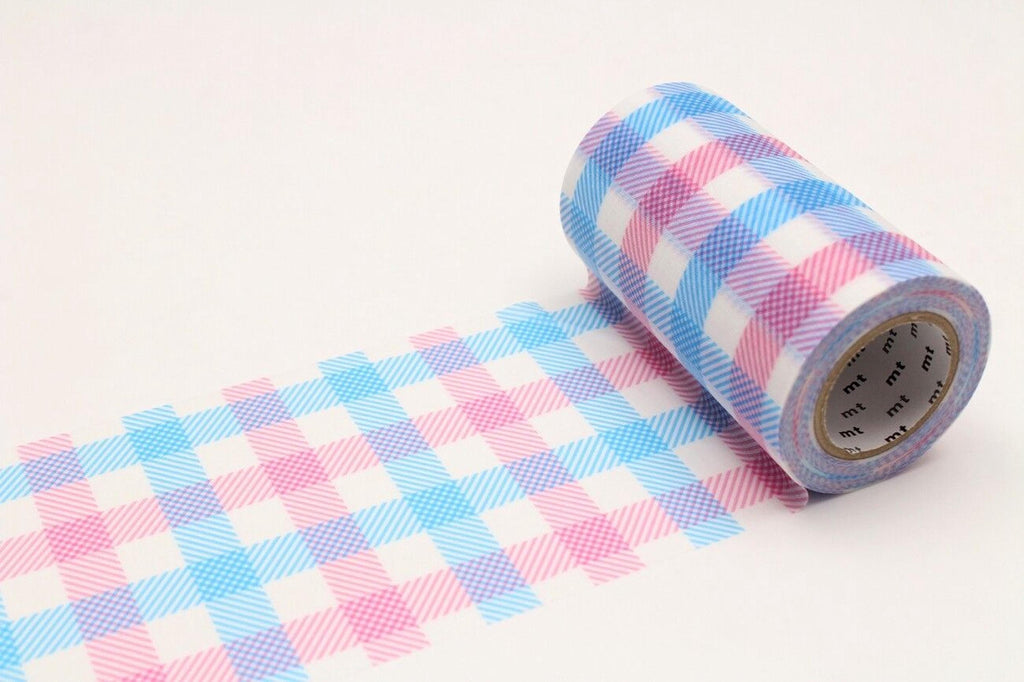 A roll of colorful tape with a checkered pattern of pink, blue, and white stripes is lying on a white surface.