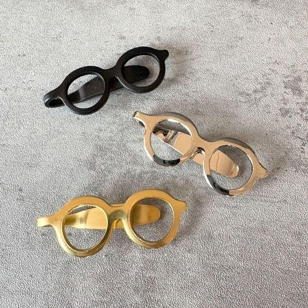 Three pairs of round-framed glasses with different colored frames are displayed on a gray surface.