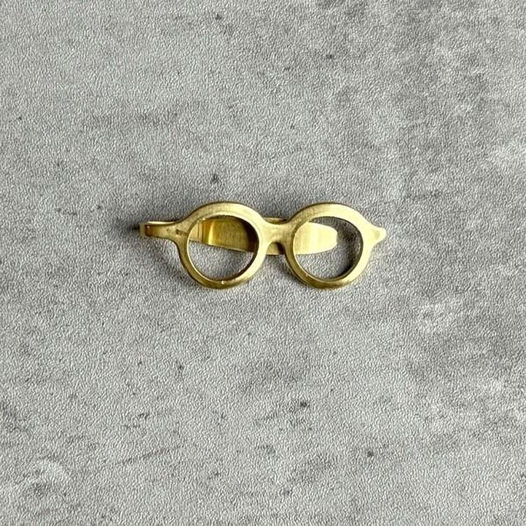 A pair of gold-colored glasses is placed on a gray surface.