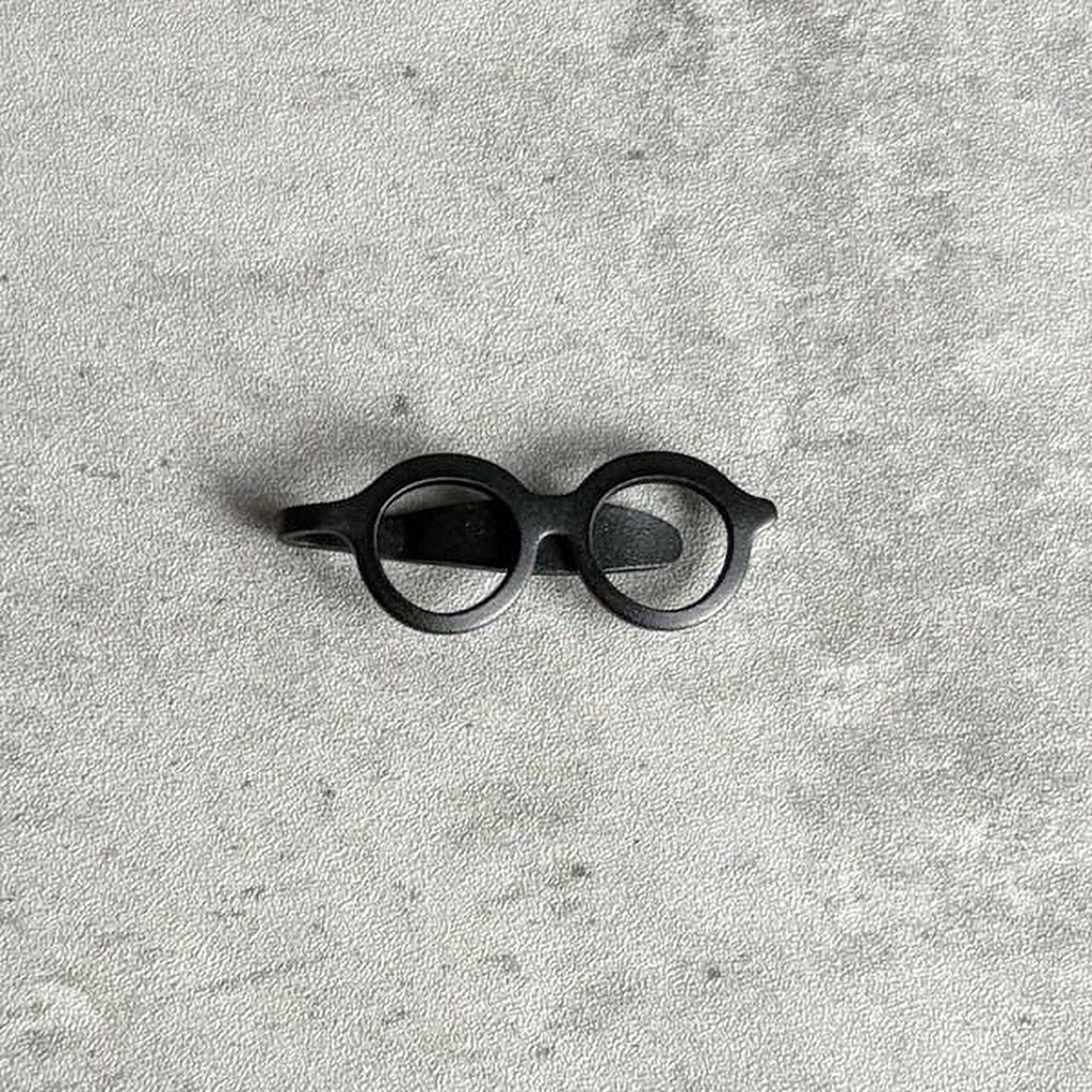A pair of black glasses is placed on a textured gray surface.
