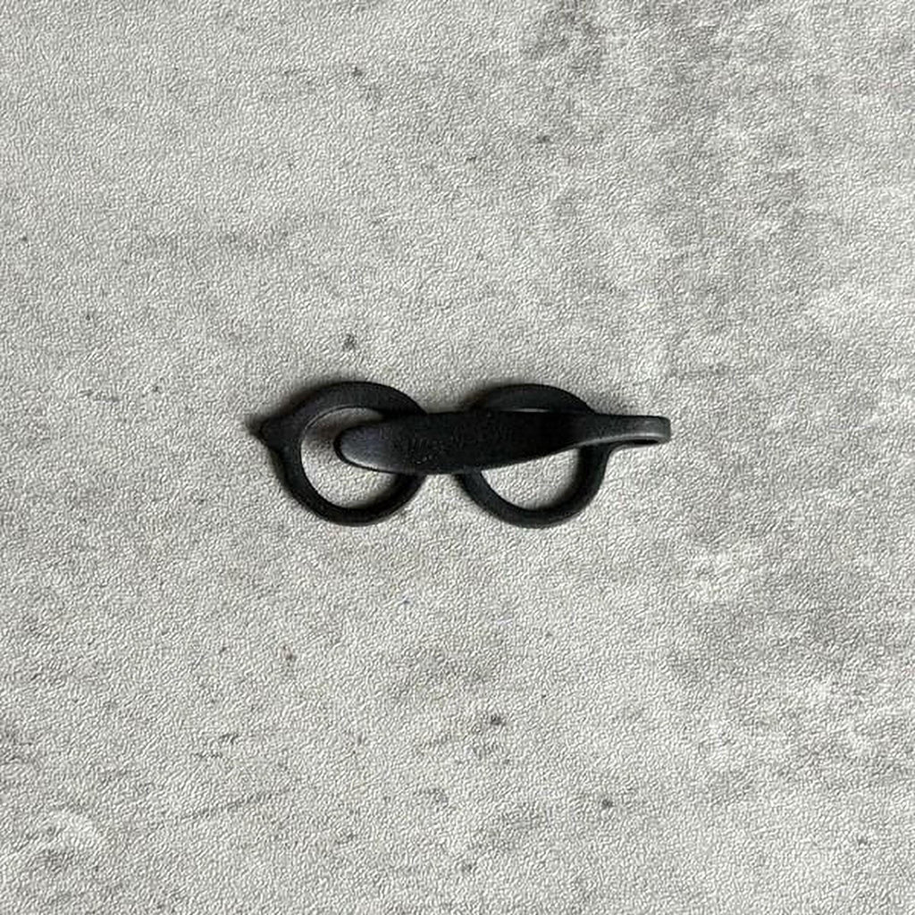 A pair of black metal scissors is lying on a textured gray surface.