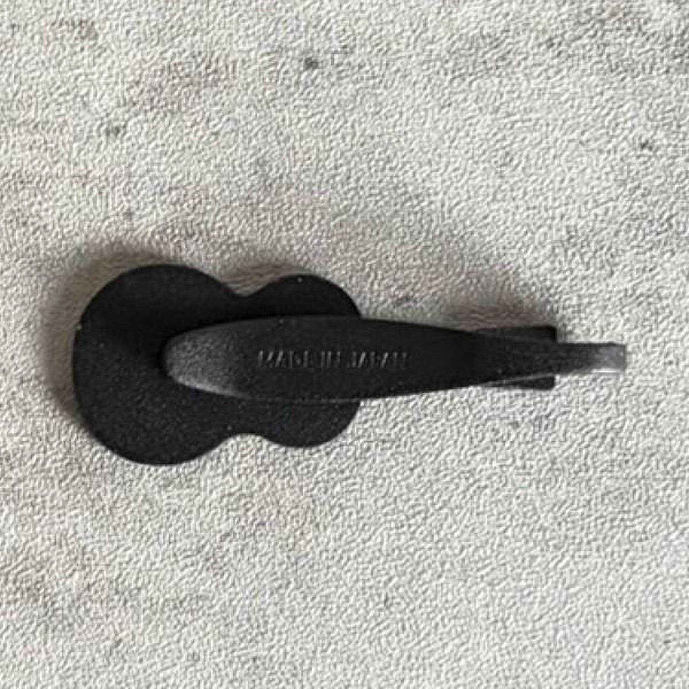 A black guitar pick lying on a textured surface.