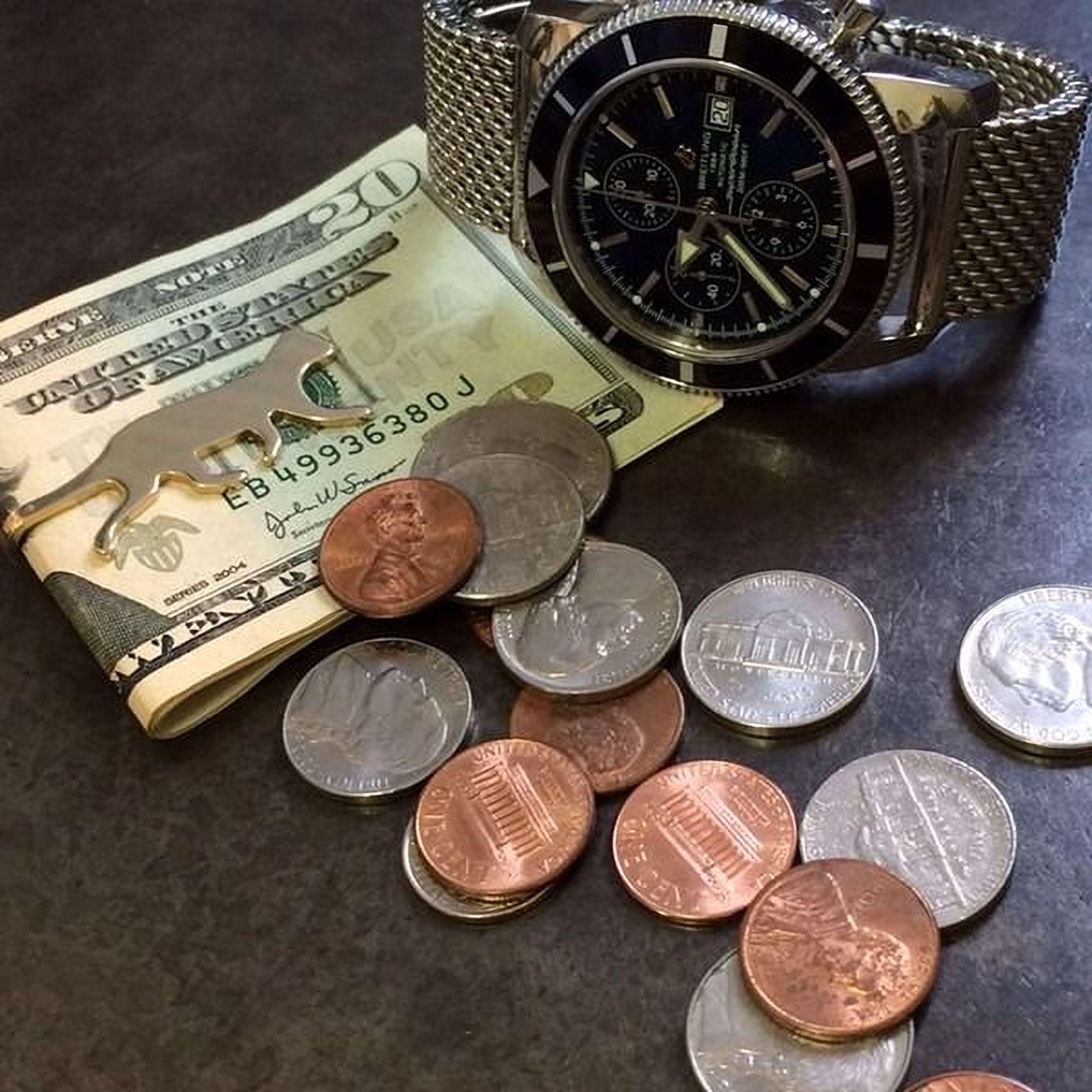 a collection of coins and a watch on a dark surface.