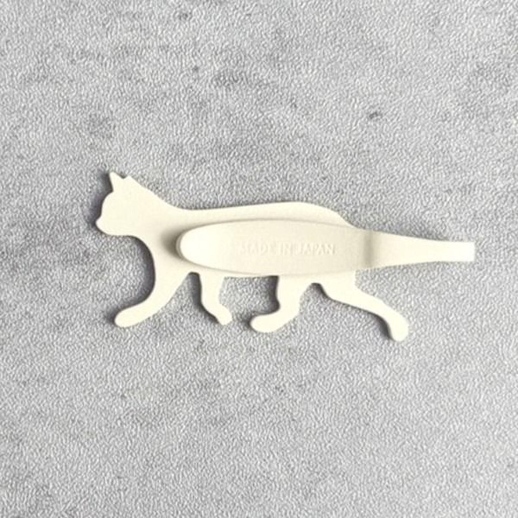 A white cat-shaped object with the text "Made in Japan" printed on it, placed on a textured gray surface.