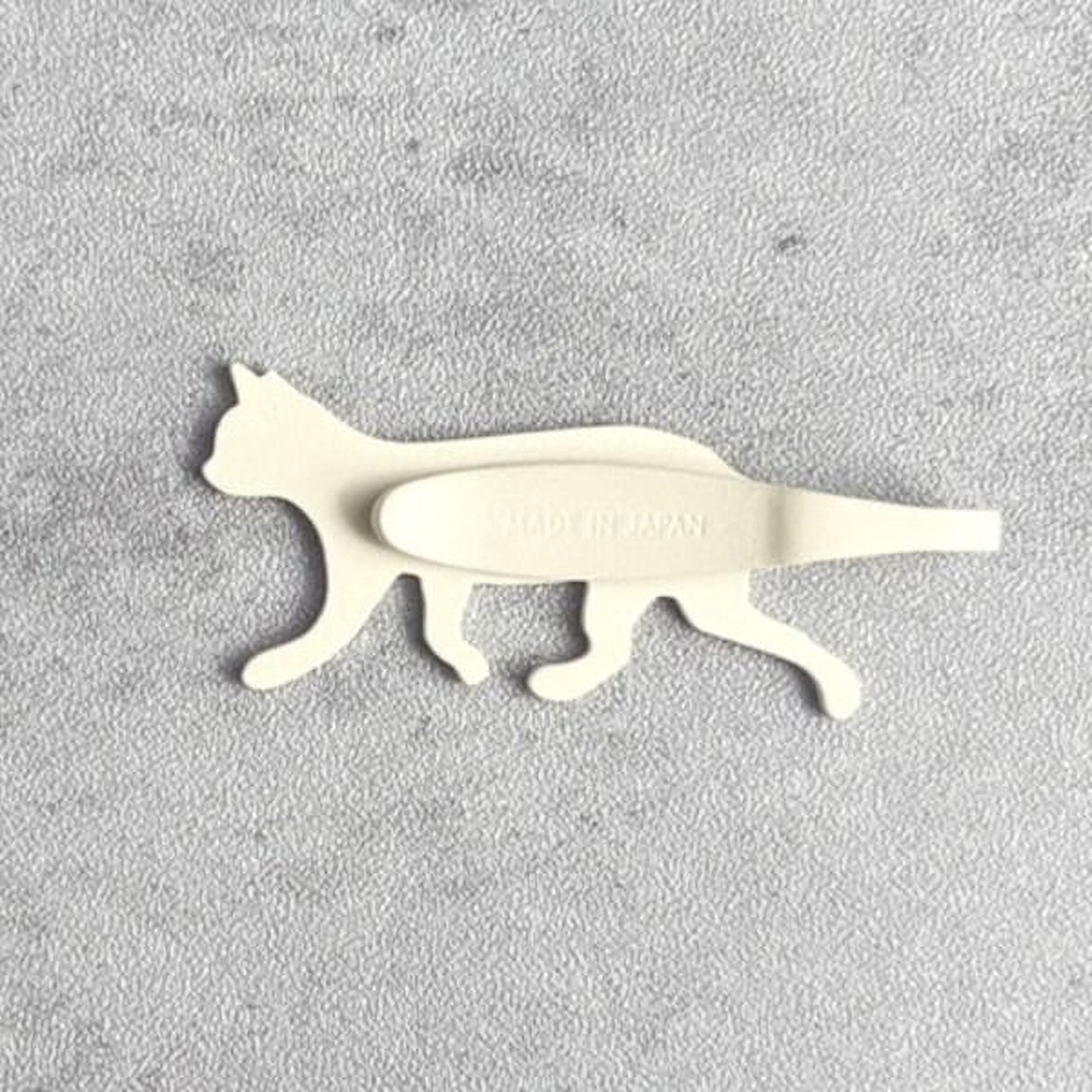 A white cat-shaped object with the text "Made in Japan" printed on it, placed on a textured gray surface.