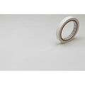 A roll of white tape is lying on a white surface.