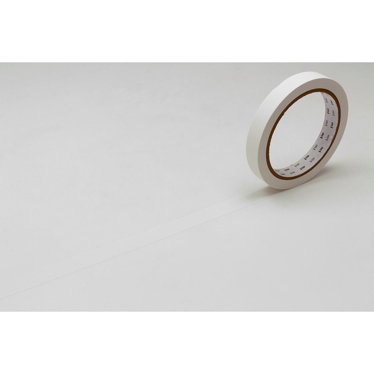 A roll of white tape is lying on a white surface.