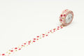 A roll of patterned tape with a floral design is placed on a white surface, with the tape extending across the image.