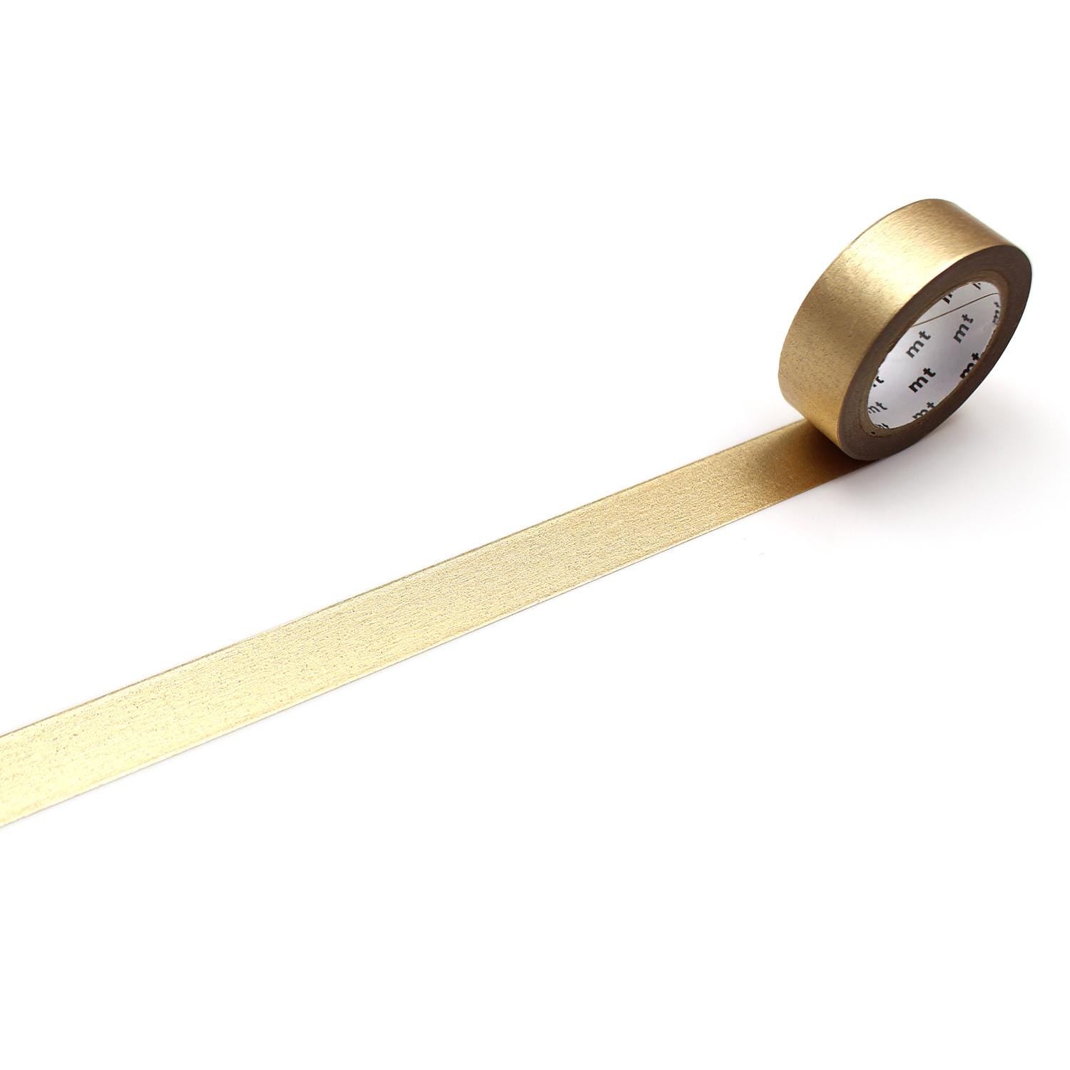 A roll of gold metallic tape is lying on a white surface, with a gold stripe running along it.