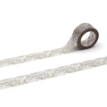 A roll of patterned tape with a floral design on it, lying on a white surface.