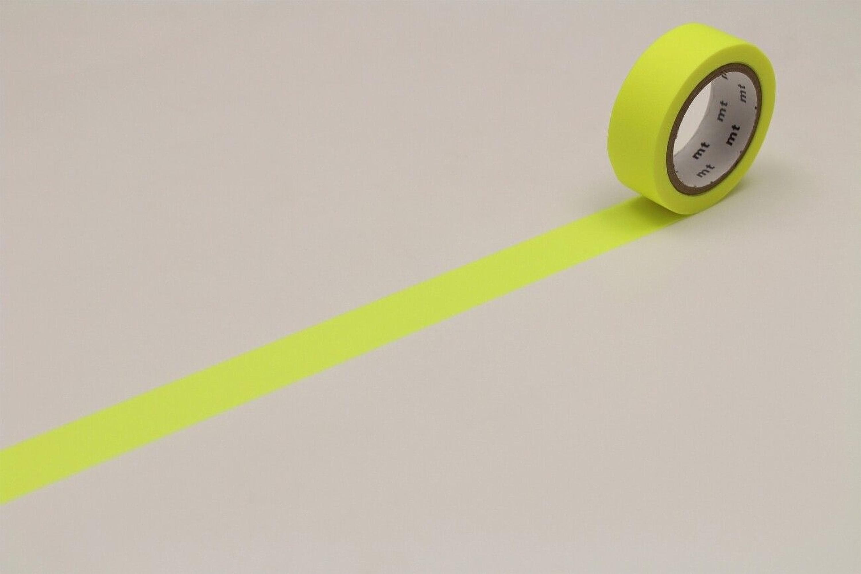 A roll of yellow tape with a black label is lying on a white surface, with a yellow line drawn on the surface.