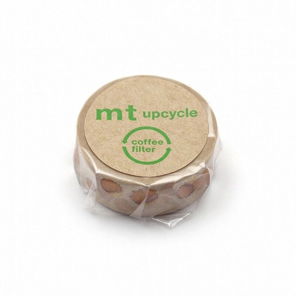 A circular object with a brown cover, featuring the text "mt upcycle" and "coffee filter" printed on it.