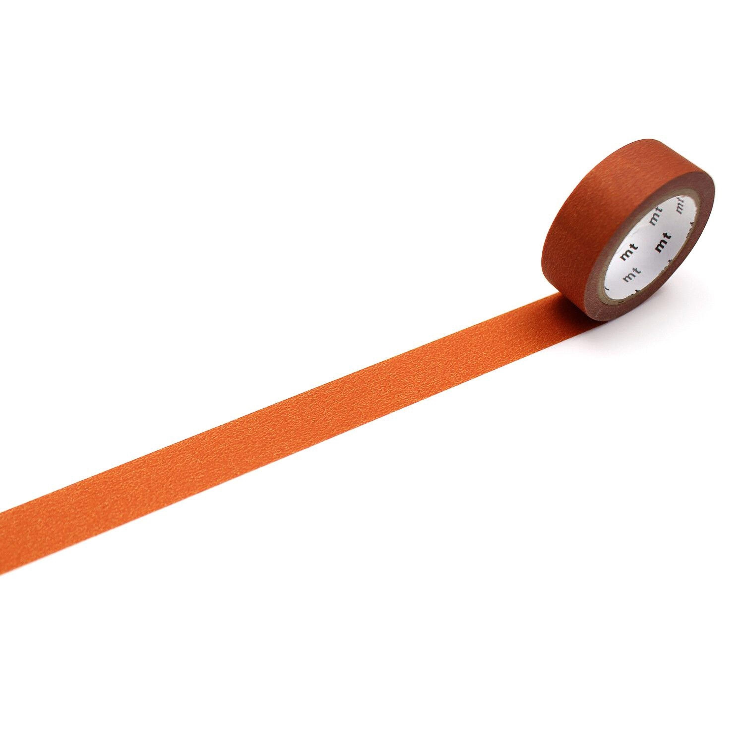 An orange-colored roll of tape is lying on a white surface, with a single line of tape extending from the roll.