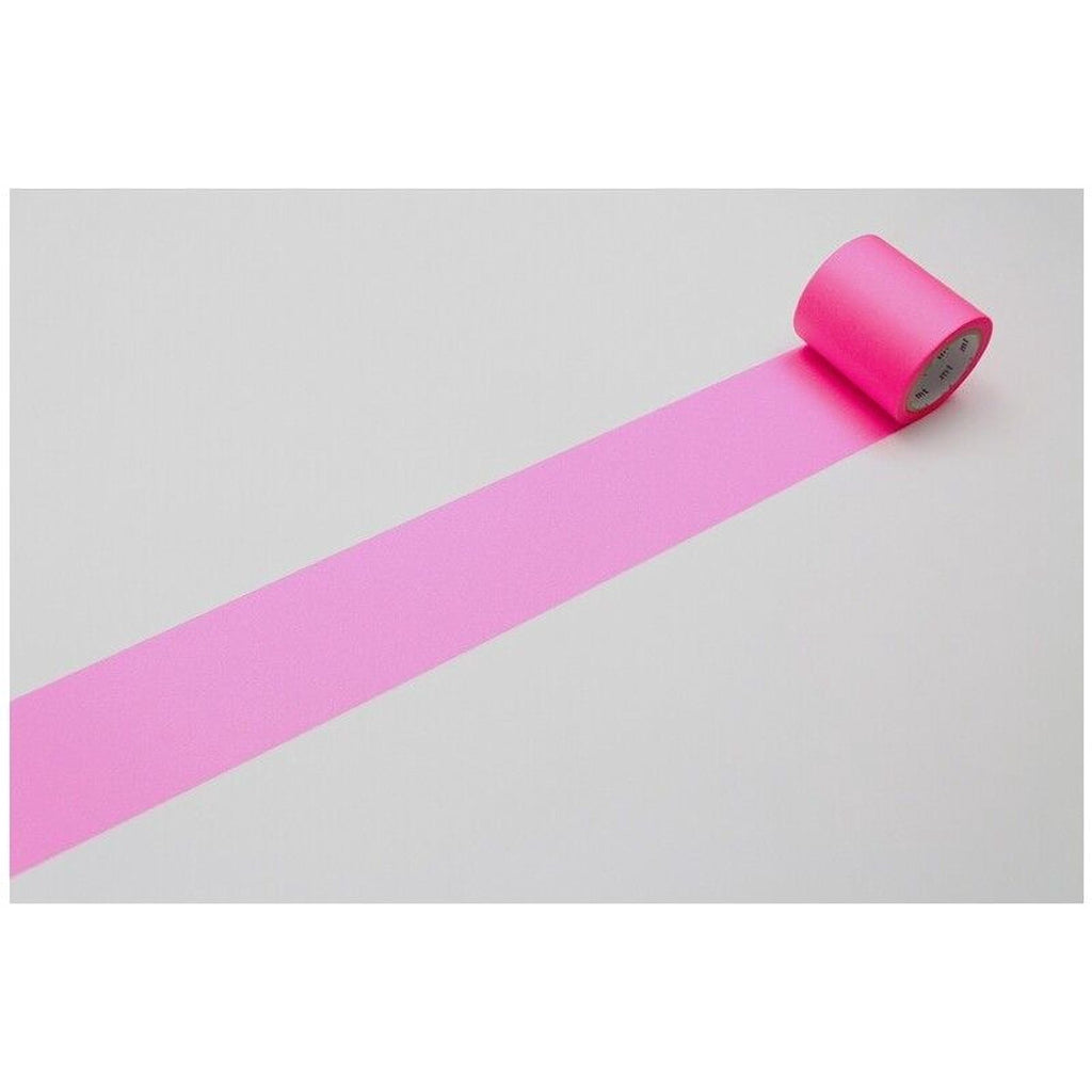 A roll of pink tape is lying on a white surface, with a single pink stripe visible on the tape.
