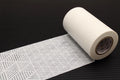 A roll of white paper towels with a geometric pattern lies on a black surface.