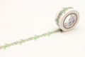 A roll of floral patterned tape is lying on a white surface, with a decorative border of green leaves and pink flowers.