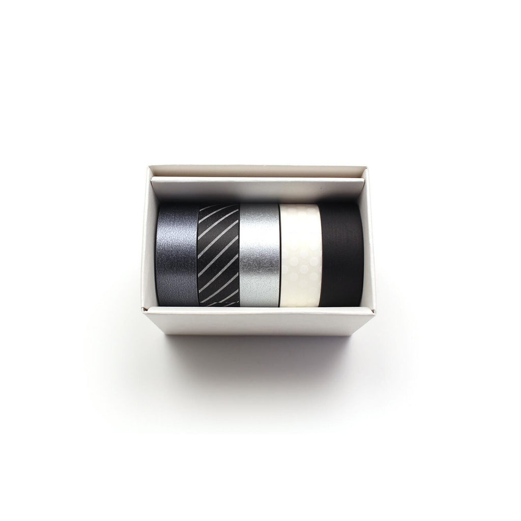 A white box containing four rolls of black, silver, and white tape.