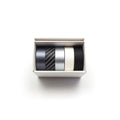 A white box containing four rolls of black, silver, and white tape.