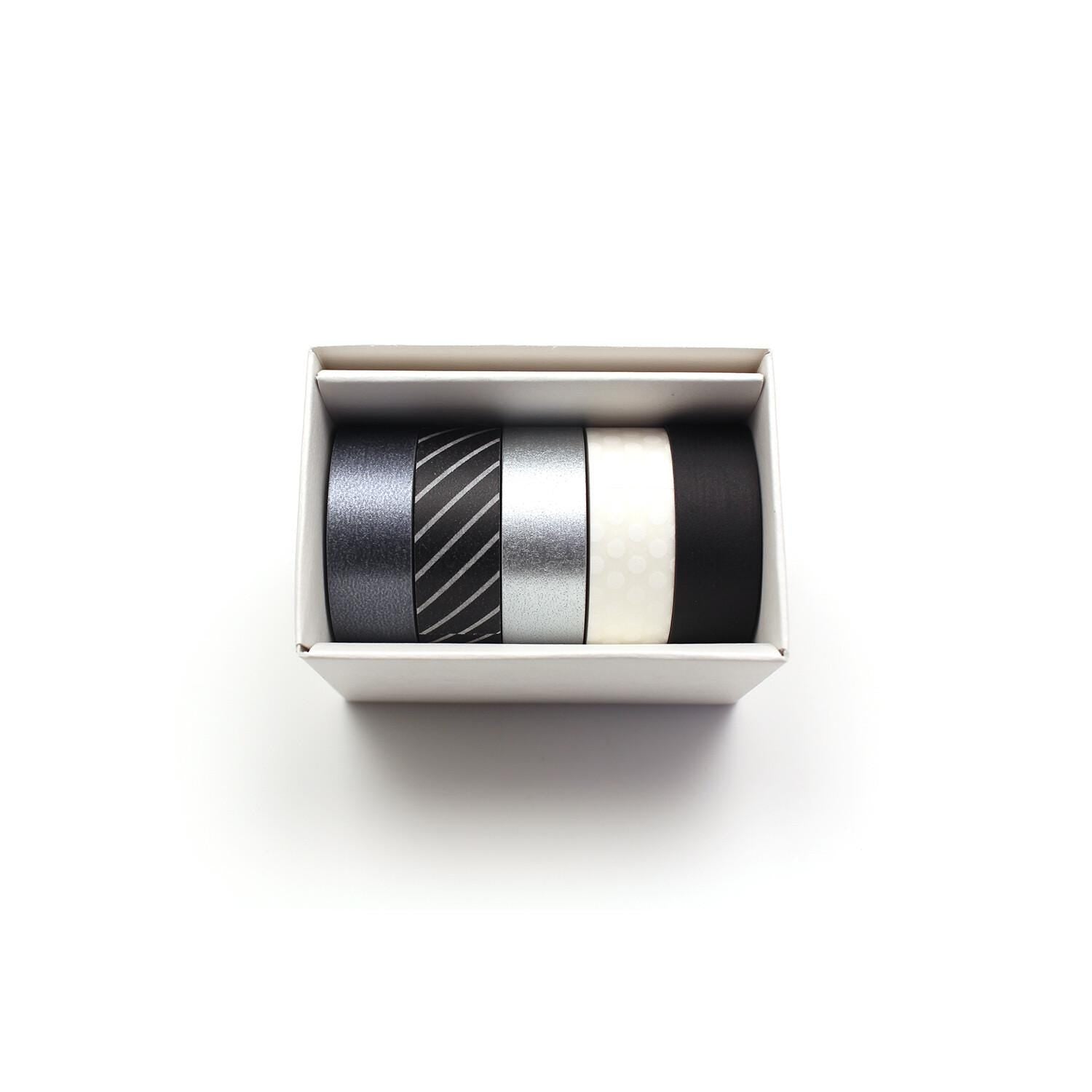 A white box containing four rolls of black, silver, and white tape.