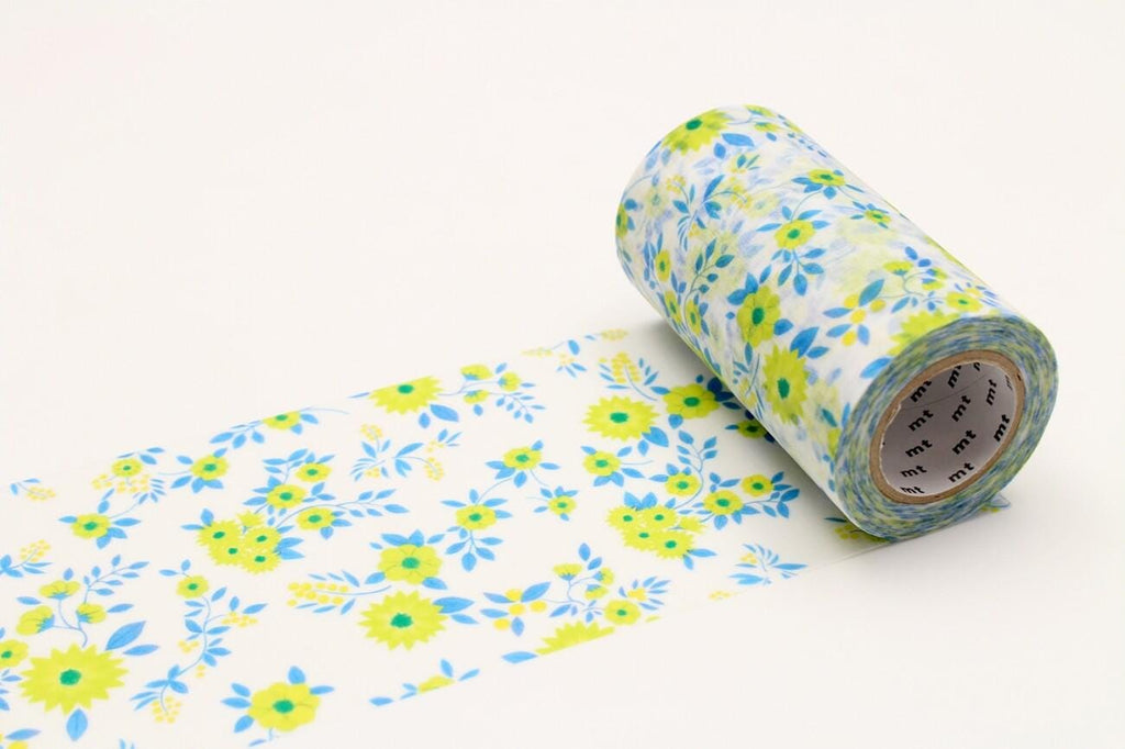 A roll of floral patterned tape is lying on a white surface, with the tape partially unwinding and revealing a pattern of yellow and blue flowers.