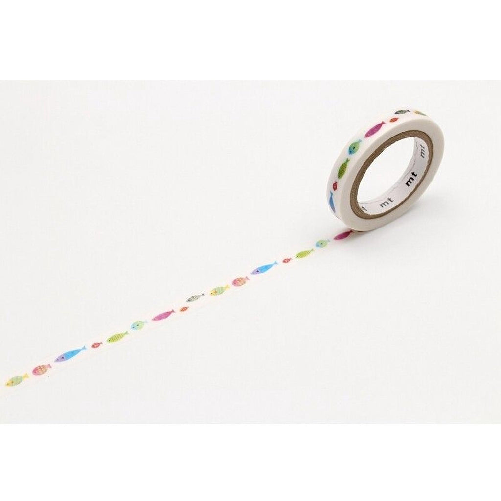 A roll of colorful fish-shaped washi tape is lying on a white surface, with a pattern of fish visible on the tape.