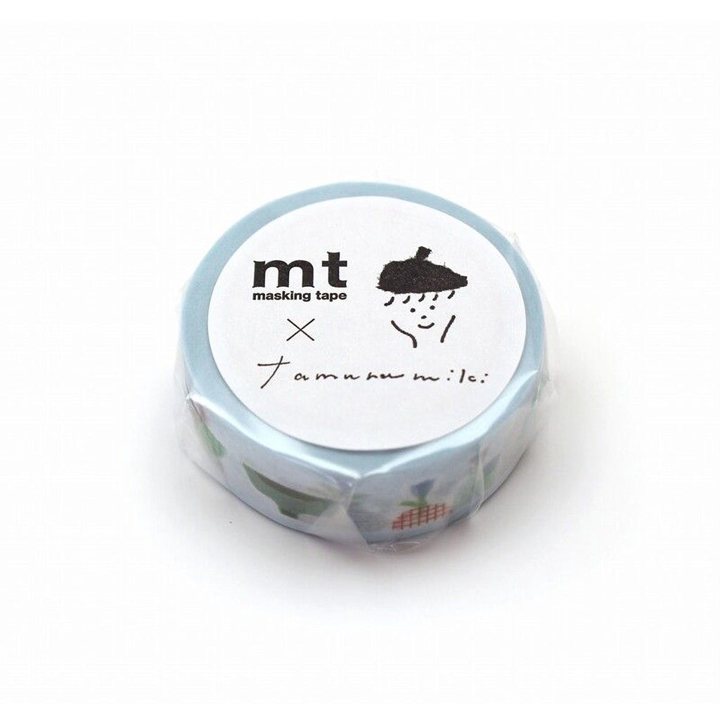 A blue and white circular object with a black drawing of a person and the text "mt masking tape" and "X x x" written on it.