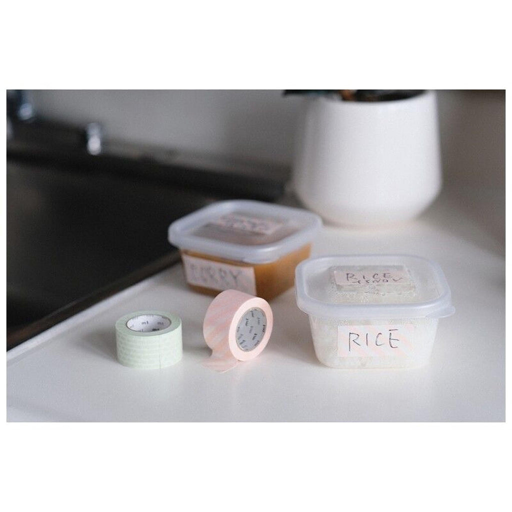 a kitchen counter with three containers labeled "Pikky", "Rice", and "Rice". There is also a roll of tape and a plant in the background.