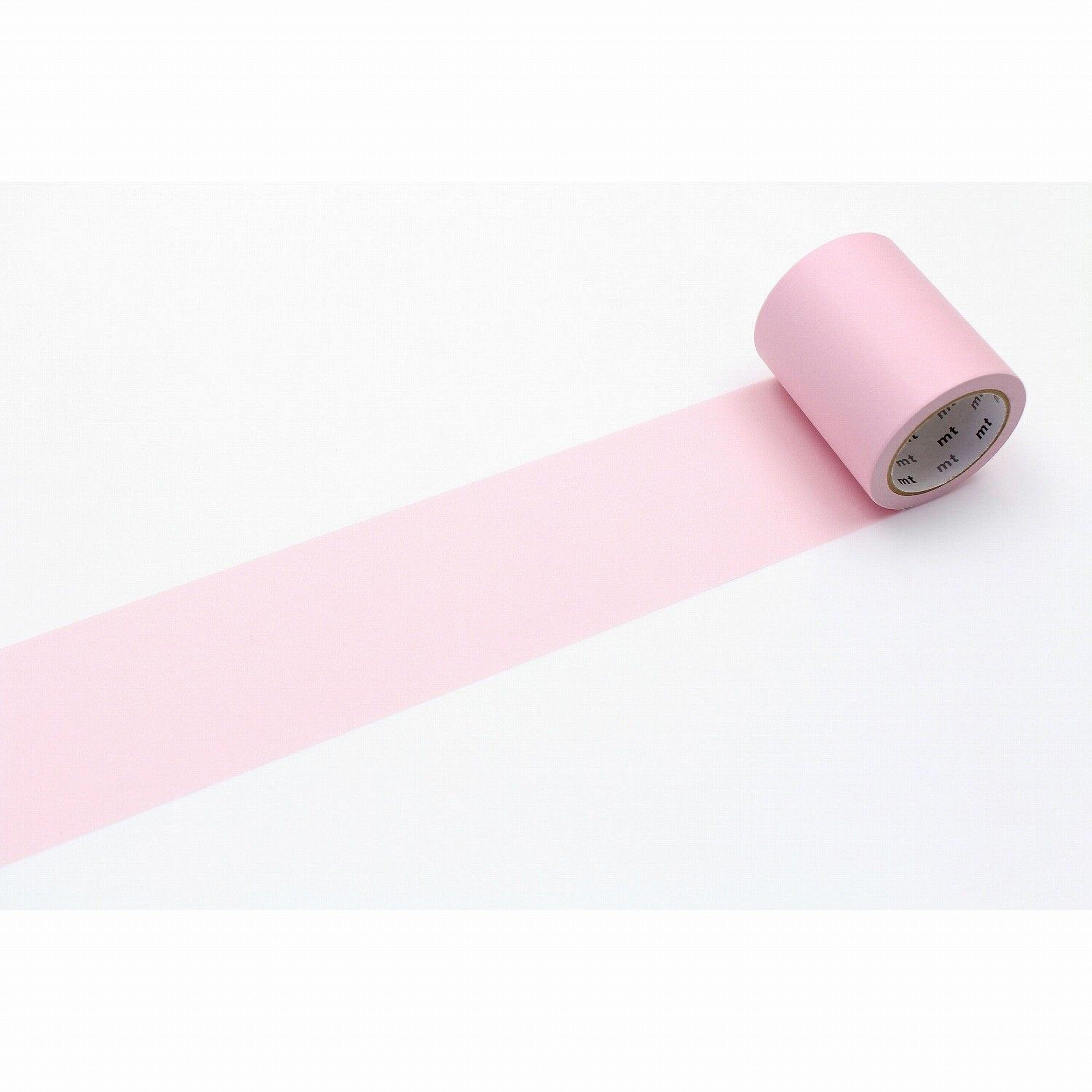 A roll of pink tape is lying on a white surface, with a pink line running across it.