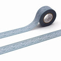 A roll of blue and gray patterned tape with a white spiral design on it, lying on a white surface.