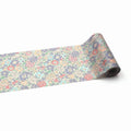 A roll of paper with a floral pattern on it, lying on a white background.