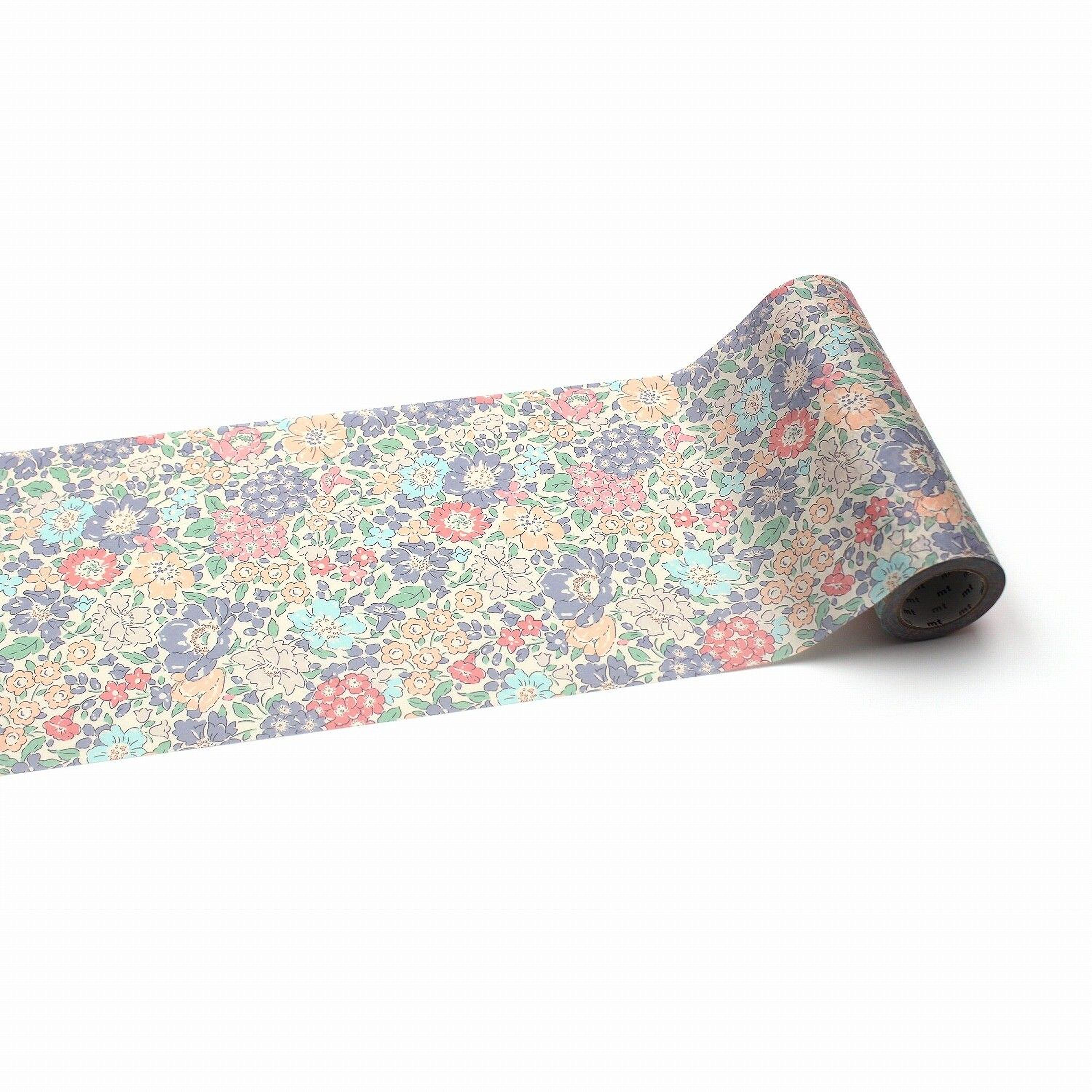 A roll of paper with a floral pattern on it, lying on a white background.