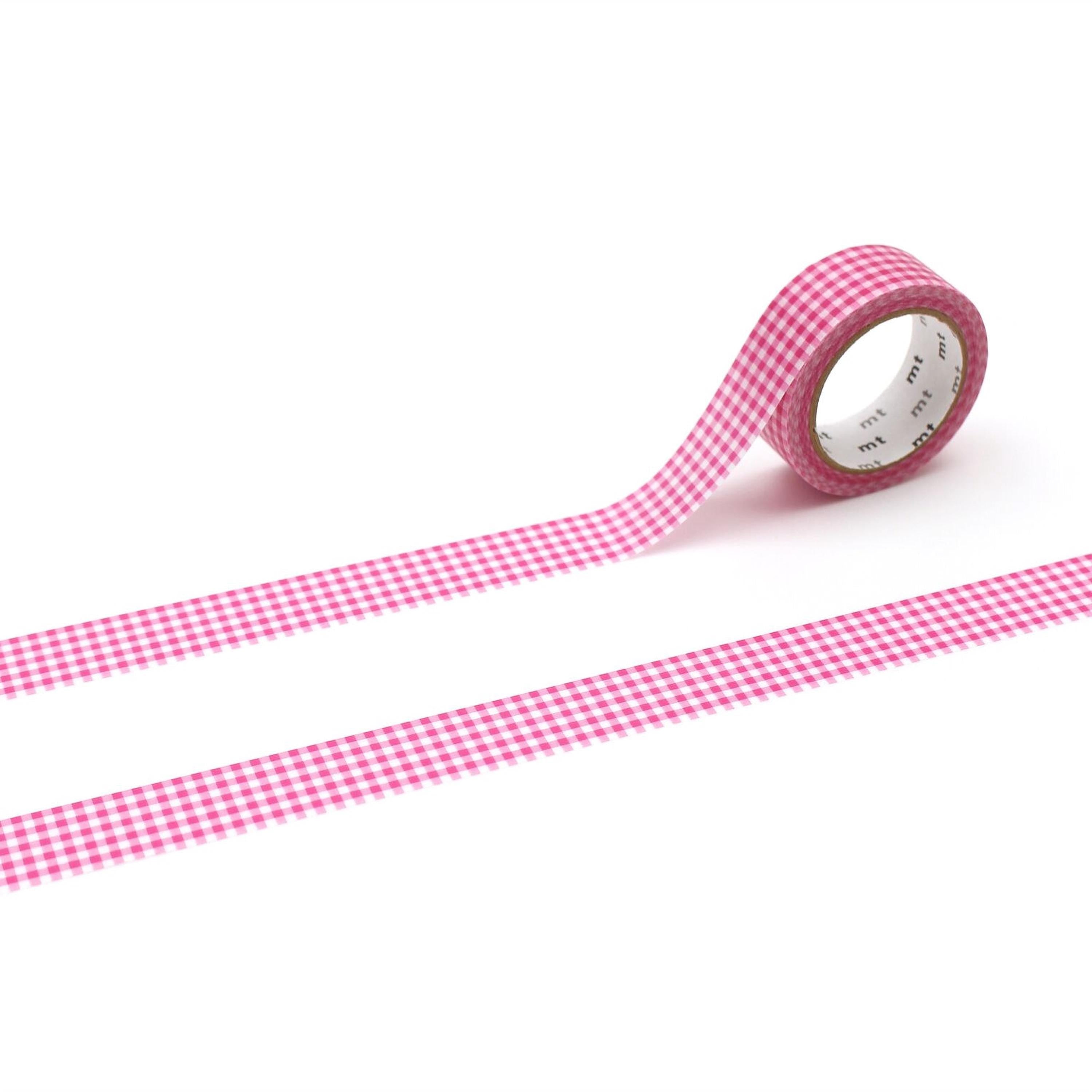 A roll of pink and white checkered tape is lying on a white surface, with the tape partially unwinding and extending across the image.