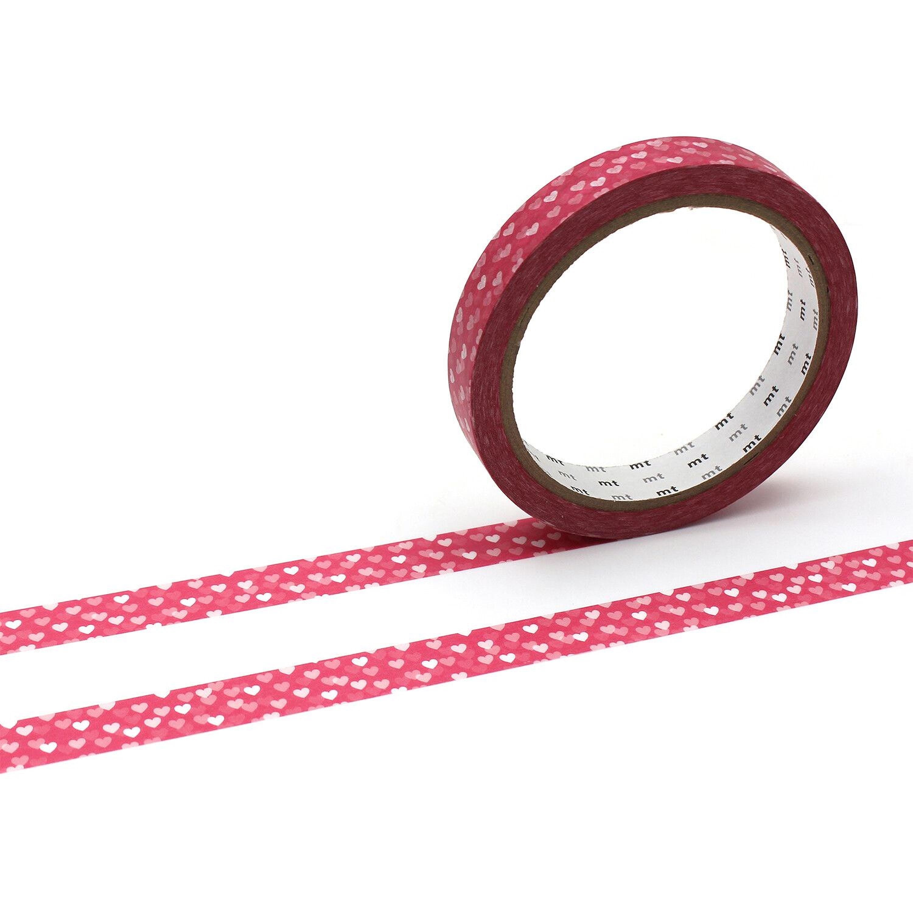 A roll of red heart-patterned tape is lying on its side on a white background, with two horizontal stripes of the same tape pattern visible.