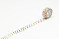 A roll of colorful polka dot tape is lying on a white surface, with a pattern of polka dots visible on the tape.