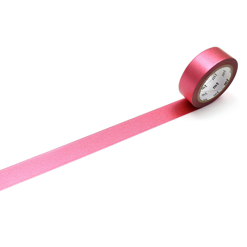A roll of pink tape with a white label is lying on a white surface, with a long pink strip extending from the tape.