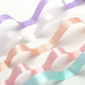 a variety of pastel-colored ribbons arranged in a wavy pattern, creating a visually appealing and vibrant display.