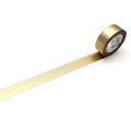 A roll of gold metallic tape is lying on a white surface, with a gold stripe running along it.