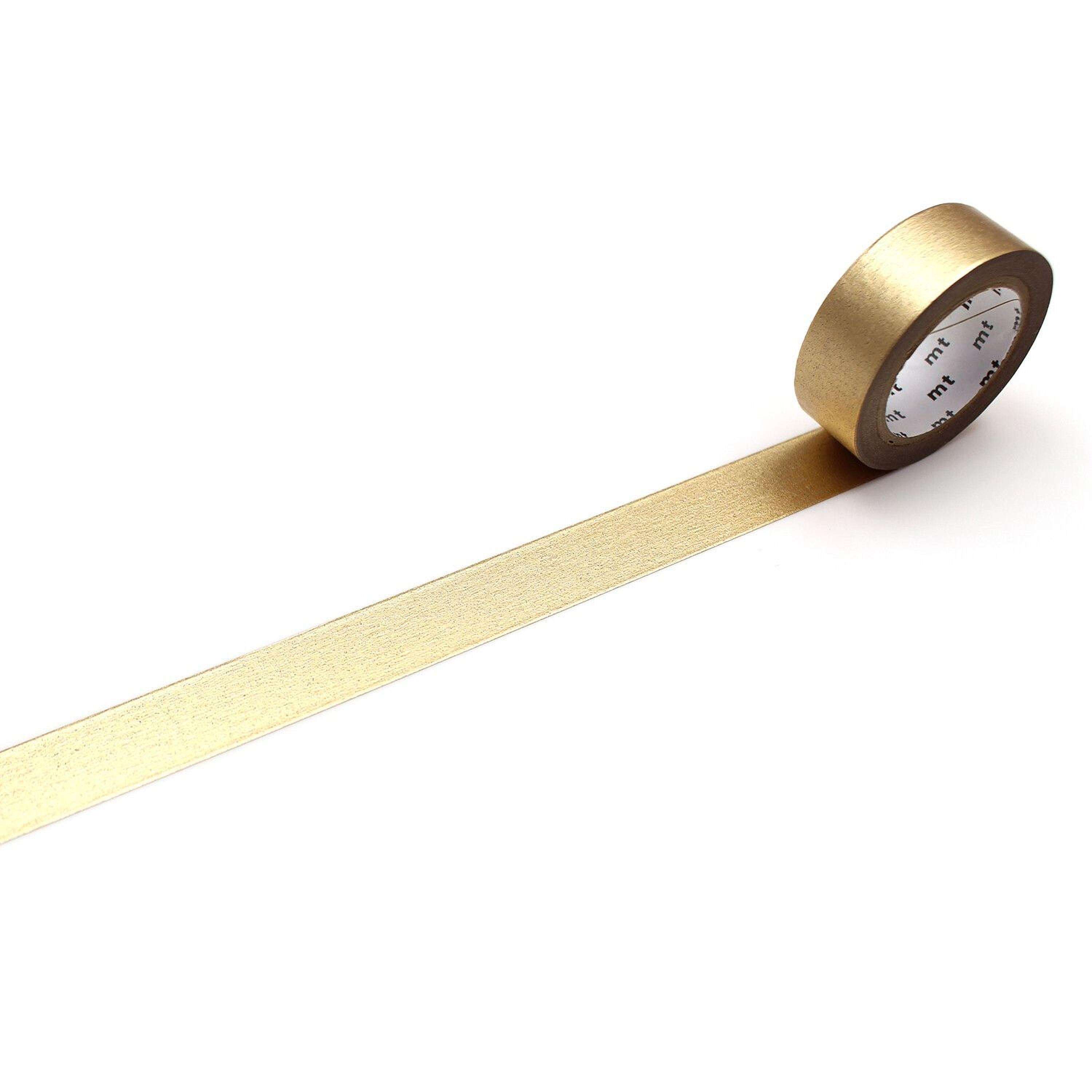 A roll of gold metallic tape is lying on a white surface, with a gold stripe running along it.