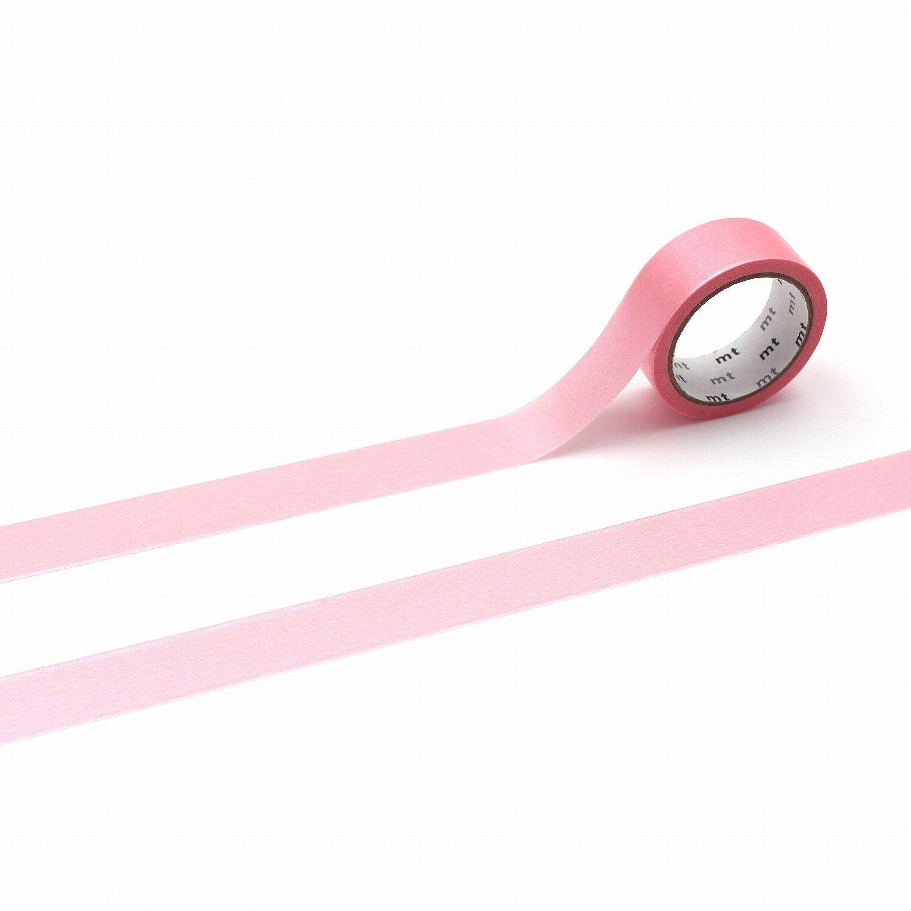 A roll of pink masking tape is lying on a white background.