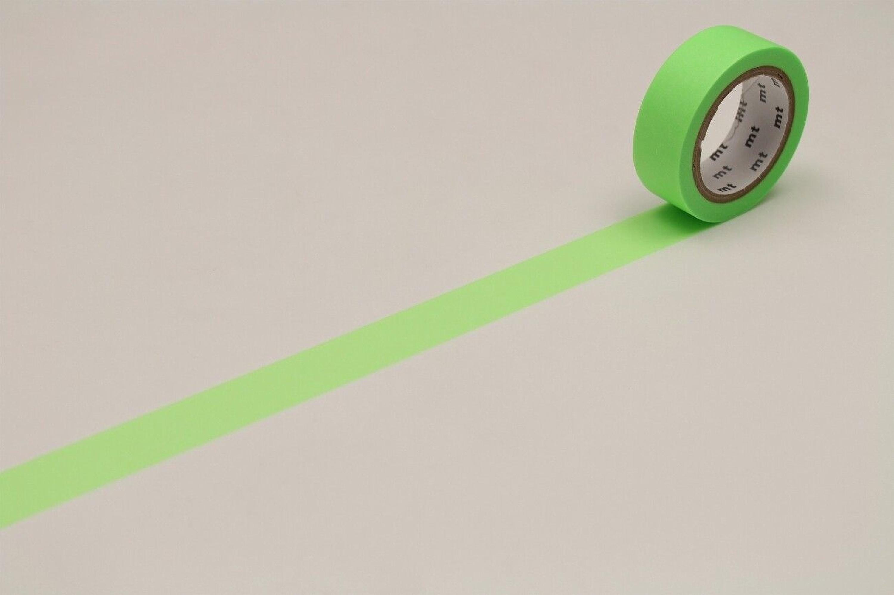 A roll of green tape with a white pattern on it is lying on a white surface, with a green line drawn on the surface.