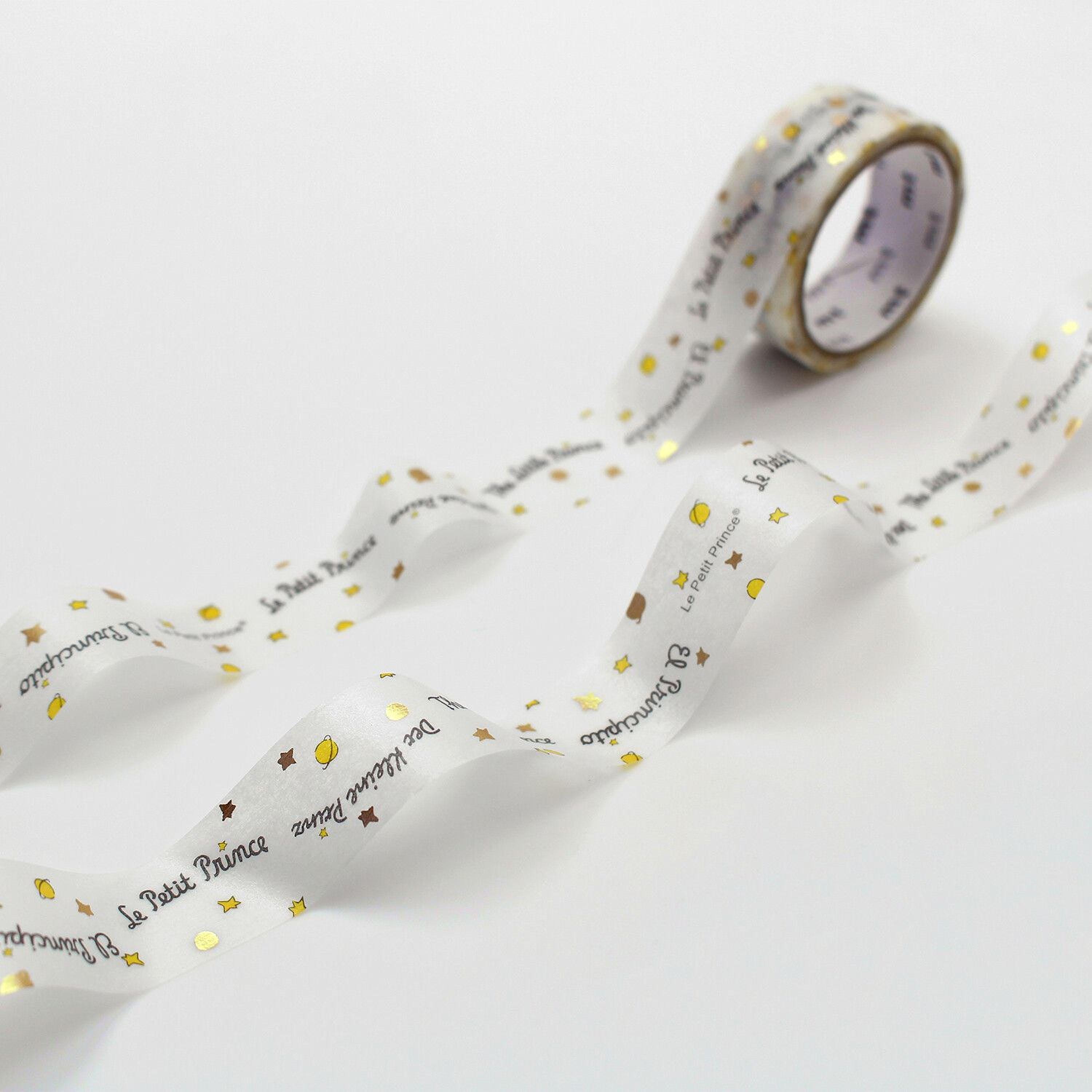 a roll of white tape with gold stars and text printed on it, lying on a white surface.