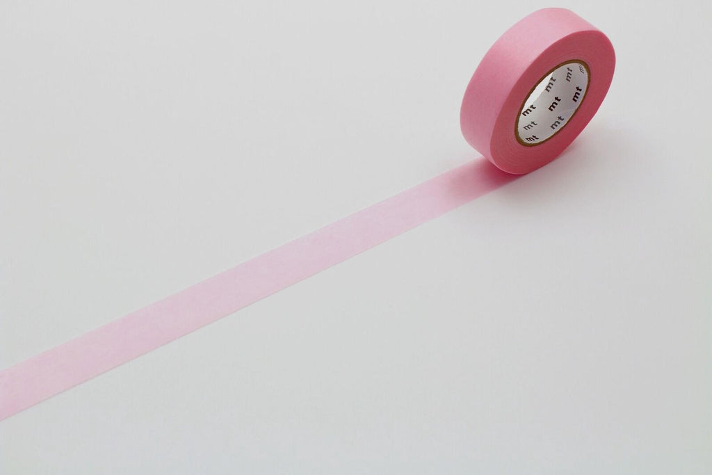 A pink roll of tape is lying on a white surface, with a single pink strip extending from the top of the tape to the bottom.