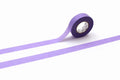 A roll of purple masking tape is lying on its side on a white background.