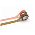 two rolls of colorful tape, one pink and one green, lying on a white background.